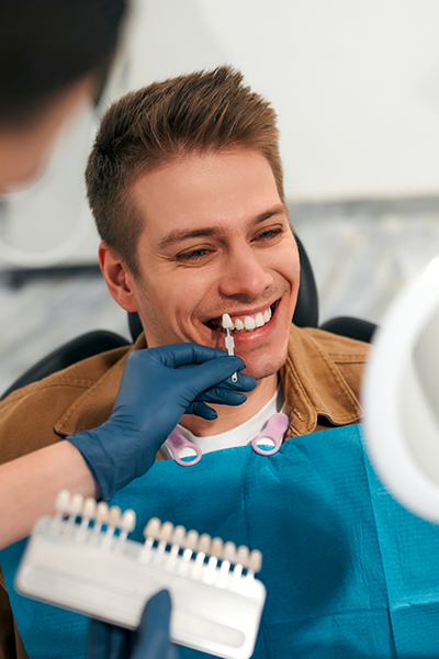 Tweezers placing a veneer over a model of a tooth