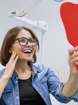 a patient checking her smile with a mirror