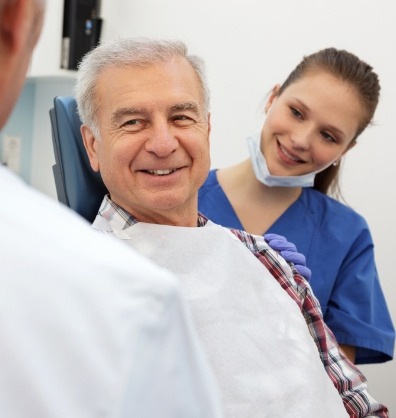 Senior dental patient smiling at his dentist