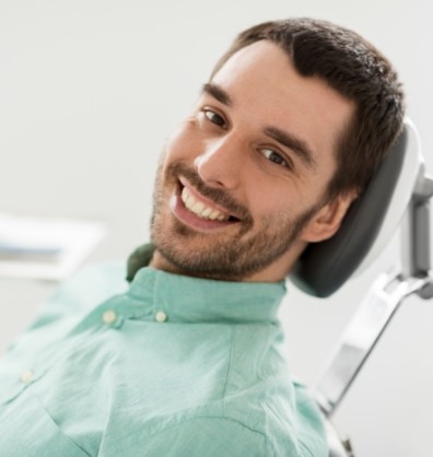 Young man leaning back in dental chair and smiling