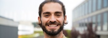 Young man with short brown beard smiling