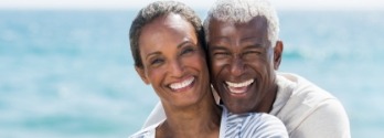 Older man and woman laughing and hugging outdoors