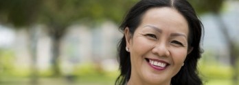 Woman with long black hair smiling outdoors