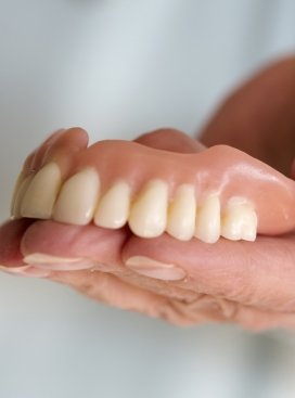 Hand holding a full upper denture