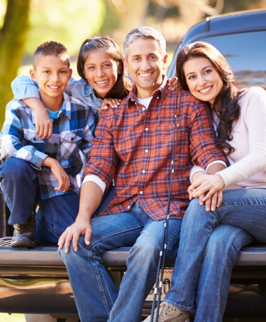 Smiling family of four sitting in truck bed