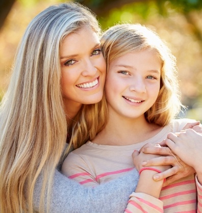 Blonde woman hugging her daughter outdoors