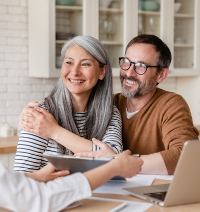 Man and woman smiling at person sitting across from them at a table