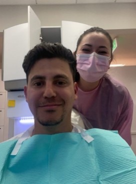 Man in dental chair taking selfie with dental team member