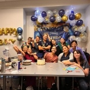 Team members at birthday party with blue silver and gold balloons