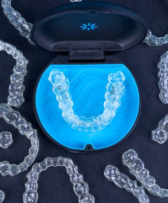 Several Invisalign clear aligners in San Jose on black table with carrying case