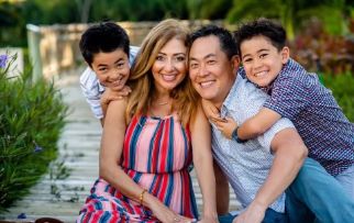 Doctor Lim and his family smiling and sitting on a boardwalk