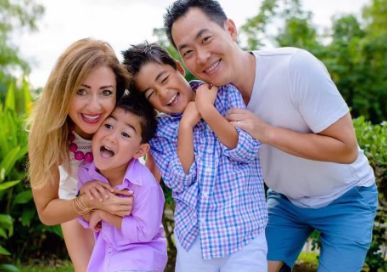 Doctor Lim and his family outdoors with green trees in background