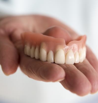 Hand holding a full denture