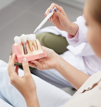 Dentist showing a model of a dental implant to a patient