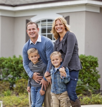 Family of four smiling in their front yard