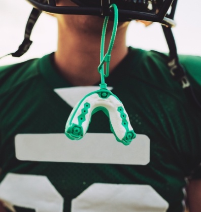 Football player with an athletic mouthguard hanging from their helmet