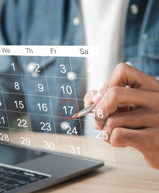 Person circling date of dental appointment on calendar