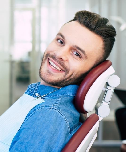 Smiling man leaning back in dental chair after restorative dentistry in San Jose