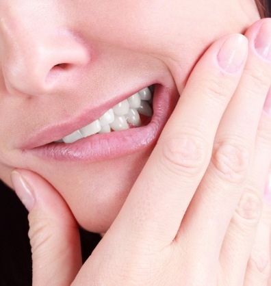 Close up of person wincing and holding their jaw in pain