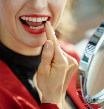 Woman with red lipstick checking her teeth in mirror