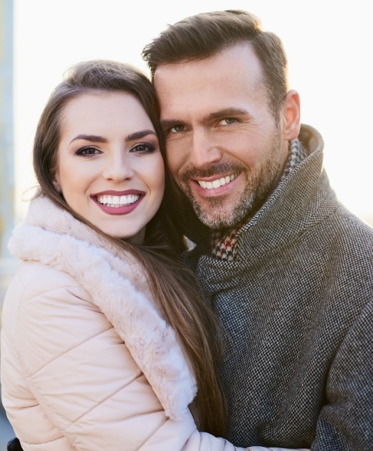 Man and woman in winter coats smiling outdoors