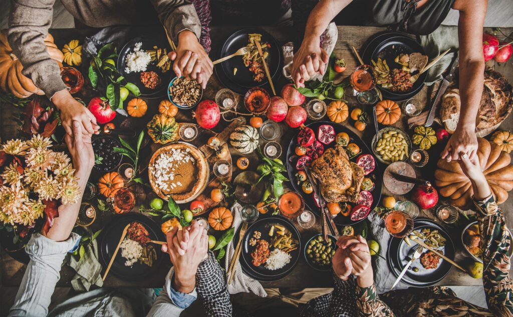 Hands held in prayer over a table full of Thanksgiving foods